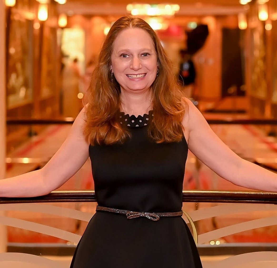 A woman in black dress standing next to railing.